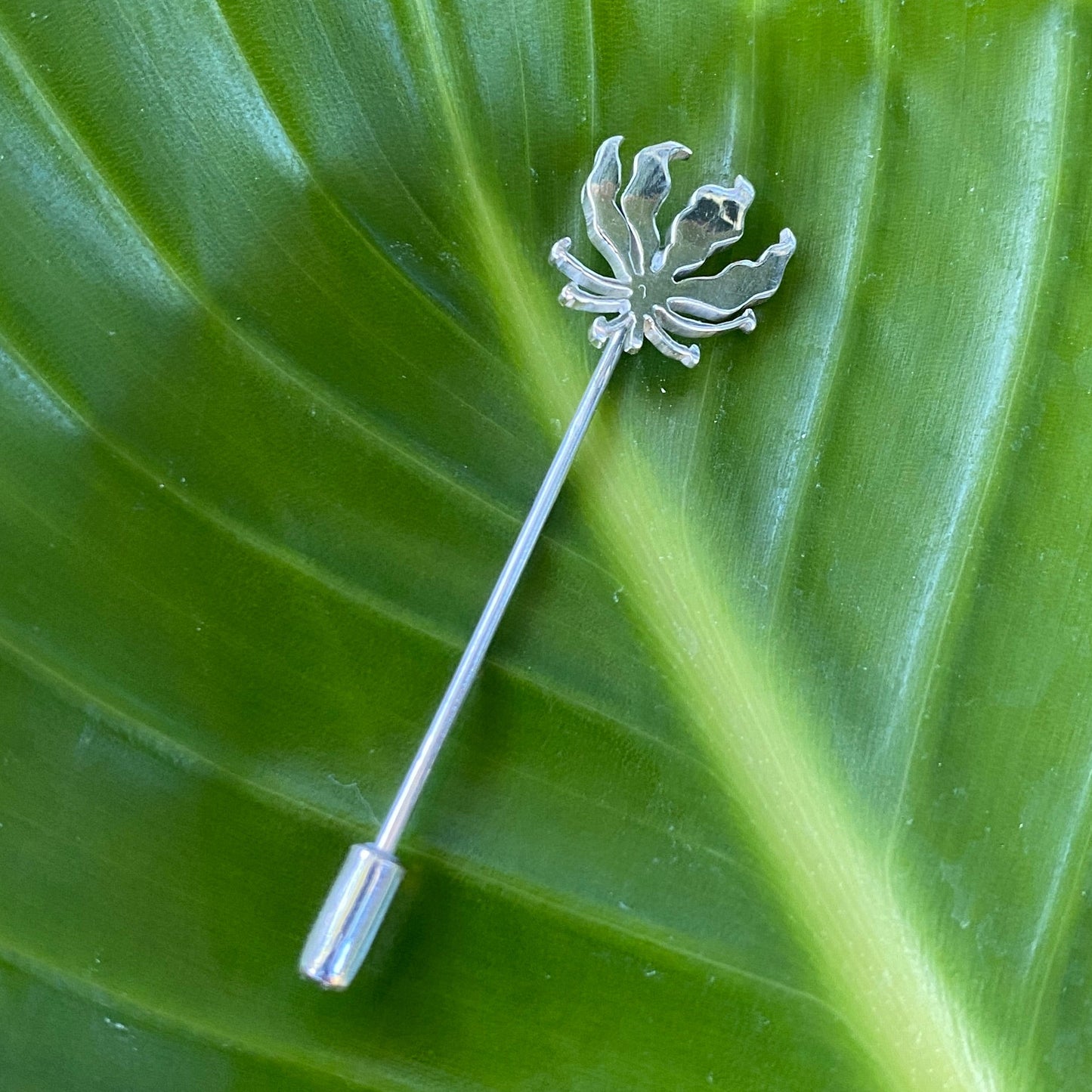 Silver Flame Lily Tie Pin on a Green Leaf