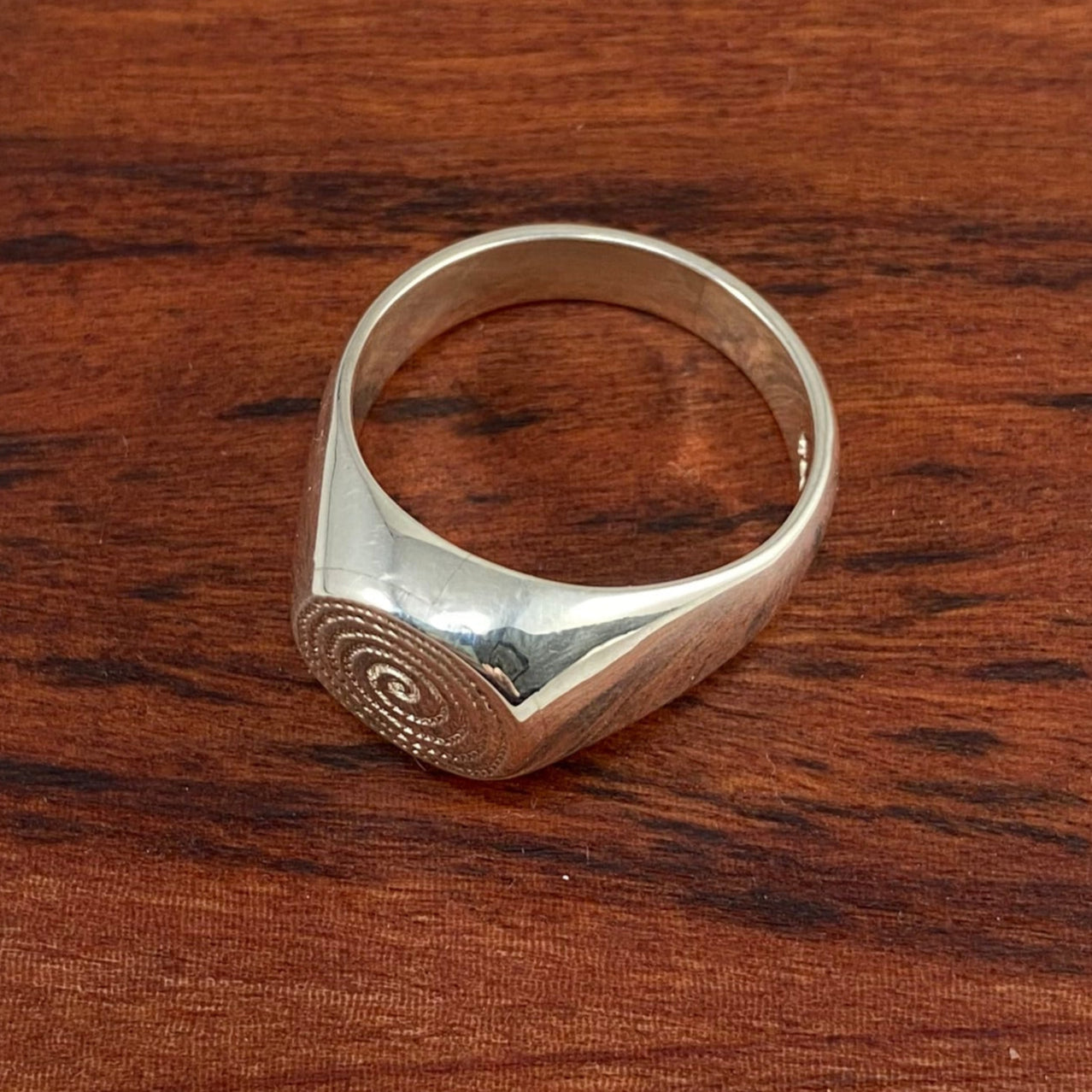 Silver ring on a wooden square block 