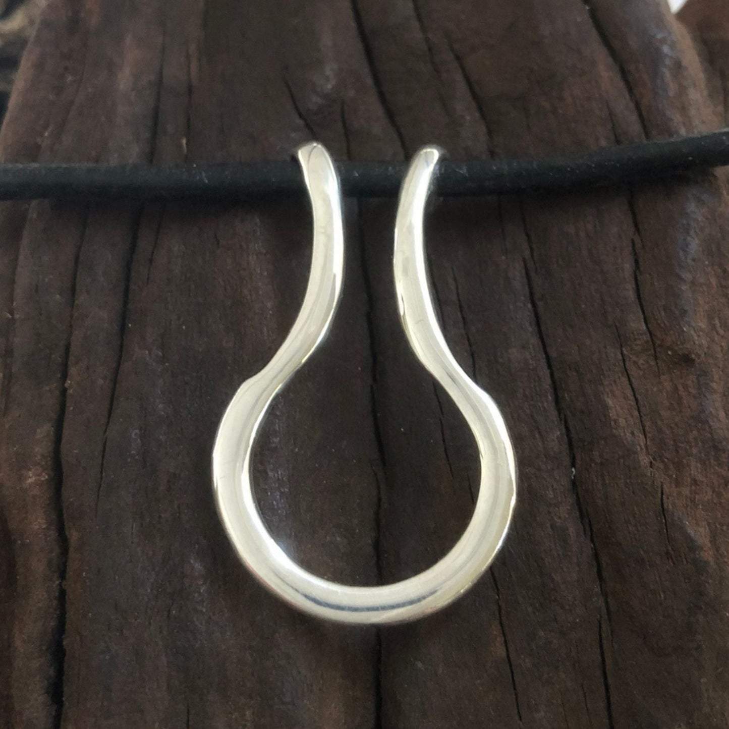 Silver ring saver pendant on a leather necklace. 