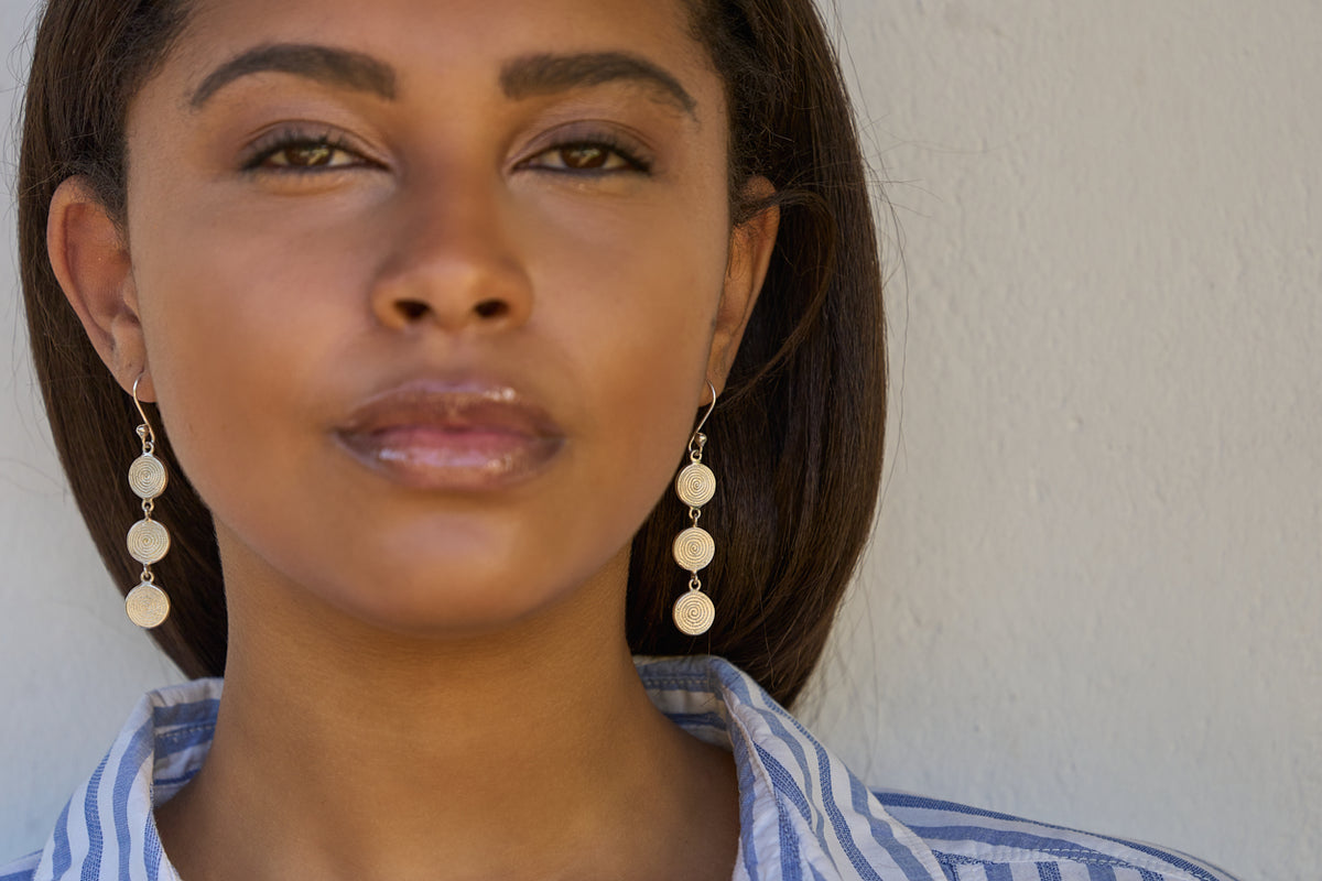 Woman wearing handcrafted sterling silver Triple Ndoro earrings by The Zuri Collection.