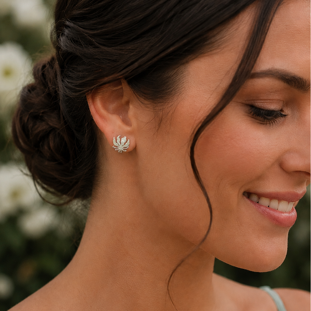 Woman wearing handcrafted sterling silver Flame Lily stud earrings inspired by Zimbabwe's national flower.
